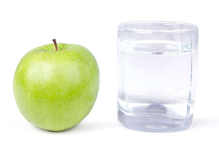 Glass of water and one green apple, closeup on whiteの写真素材