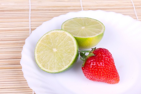 Strawberries and lime on white plate, closeup の写真素材
