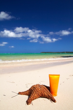 Starfish and sun tan tube on sand, closeupの写真素材