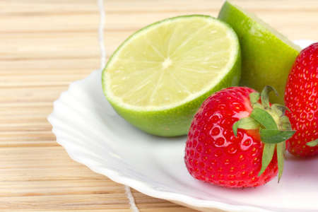 Strawberries and lime on white plate, closeup の写真素材