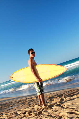 Surfer holding a surfboard on tropical beachの写真素材