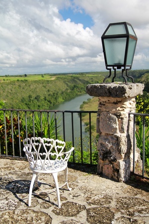 Old chair in Altos de Chavon cafe with view on tropical riverの写真素材