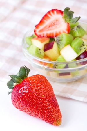 Strawberry and fruit salad in white plate on tablecloth, closeupの写真素材