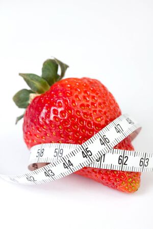 Strawberry with measure tape, closeup on whiteの写真素材