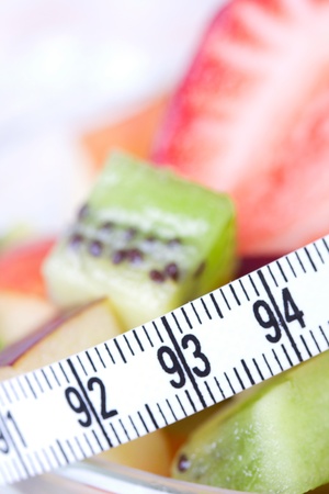 Fruit salad in white plate with measure tape, closeupの写真素材