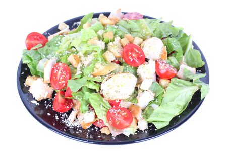Caesar salad on black plate isolated on whiteの写真素材