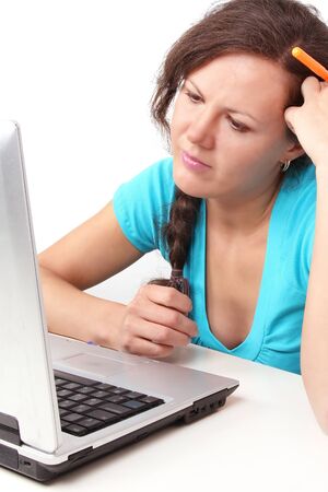 Woman looking at laptop with pen in hand, closed-up portraitの写真素材