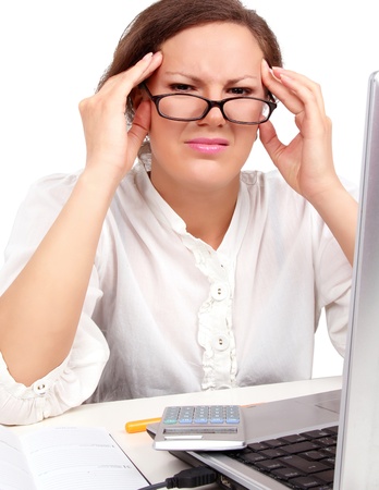 Tired businesswoman holding her head, sitting in officeの写真素材