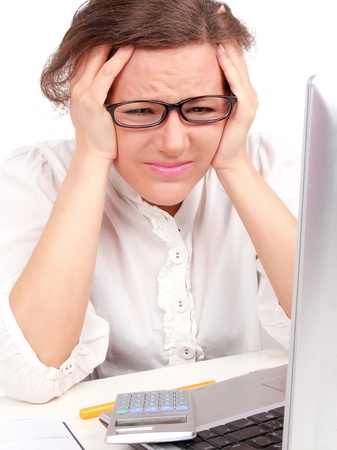 Depressed businesswoman holding her head, sitting in officeの写真素材