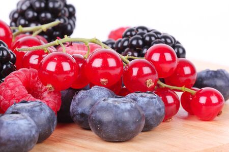 Different berries on wooden mat, closeup on whiteの写真素材