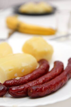 Fried sausages and boiled potatoes, closeup on plateの写真素材