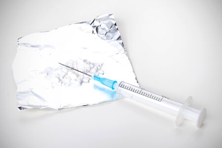 Syringe and heroin on foil, closeup on white backgroundの写真素材
