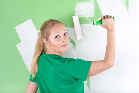 Young woman with paint roller in hand, full length portraitの写真素材