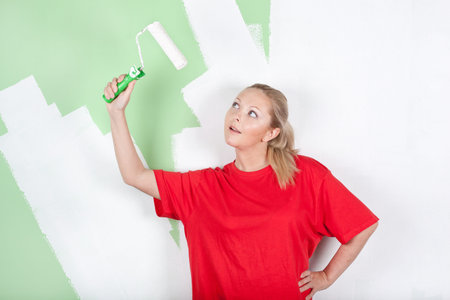 Young woman looking on paint roller in hand