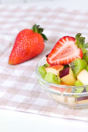 Strawberry and fruit salad in white plate on tablecloth, close up の写真素材