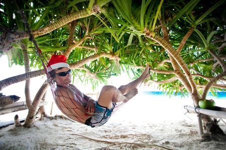 Man in Santa hat in hammock on tropical beachの写真素材