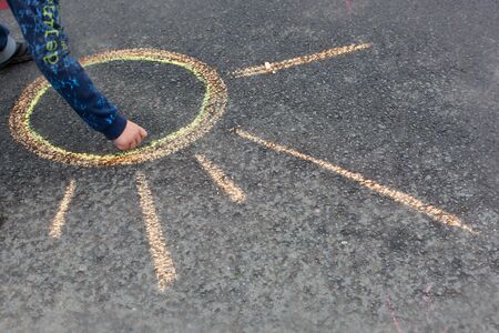 Child drawing sun on asphalt  by chalksの写真素材