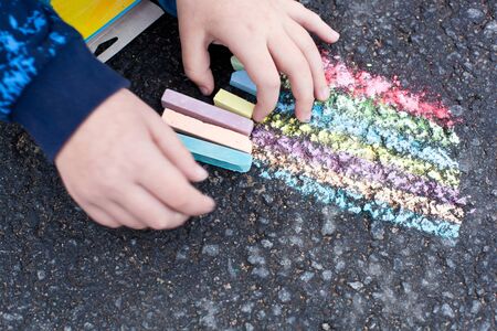 Child hand with colorful chalk on asphaltの写真素材