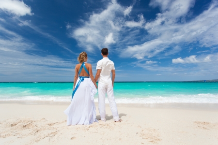 Loving wedding couple on beach in white dressesの写真素材