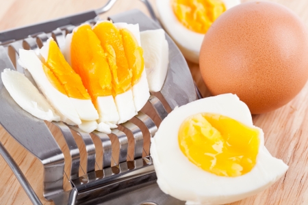 Egg cutter and cutted eggs on wooden board, closeupの写真素材