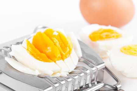 Cutted egg on cutter, closeup on white 
