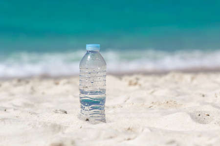 Drinking water in bottle on sand on beachの写真素材