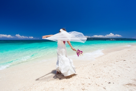 Happy dancing bride on beach in wedding dressの写真素材