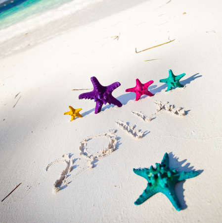 Numbers 2014 on white sandy beach with color starfishesの写真素材