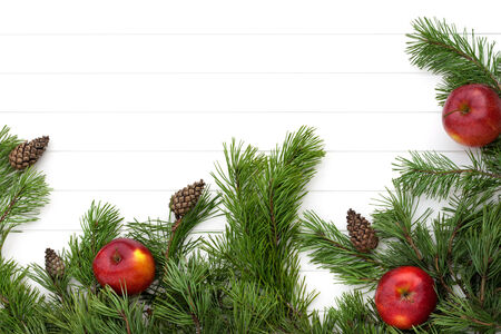 Decorated pine branches with cones and red apples on white wooden tableの写真素材