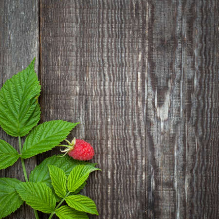 Old wooden board decorated raspberry and leavesの写真素材