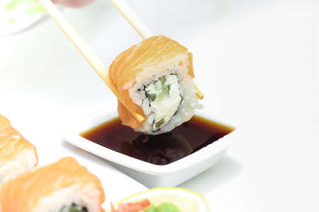 Sushi roll Philadelphia in chopsticks,  closeupの写真素材
