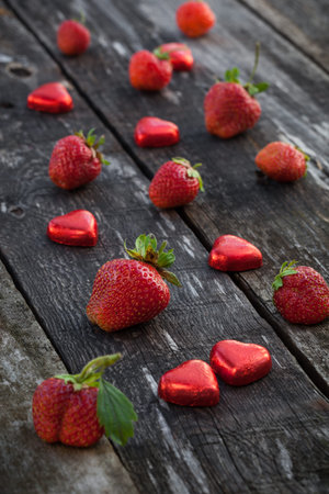 Fresh red strawberries and chocolate heart candy on old wooden tableの写真素材