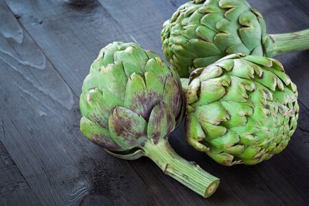 Fresh green artichokes on wooden boardの写真素材