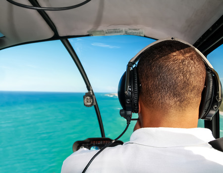Helicopter pilot in flight with caribbean sea aerial viewの写真素材