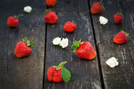 Fresh red strawberries on old wooden table decorated white flowers, selective focusの写真素材