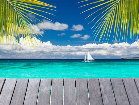 Wooden pier with view on sailboat in the oceanの写真素材