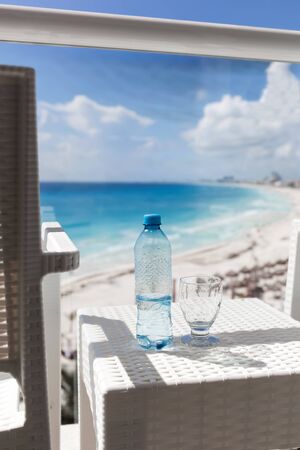 Balcony with plastic bottle of water on wicker table overlooking an oceanの写真素材