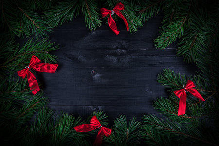 Christmas garland with red bows on rustic wooden texture with copy space