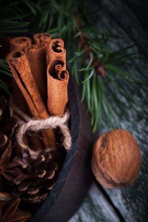 Christmas decoration card with evergreen fir tree, cones, cinnamon on rustic wooden background. Selective focus, shallow dofの写真素材