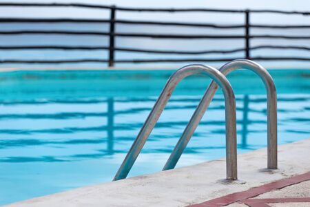 Grab bars ladder in swimming pool, outdoors at the day timeの写真素材