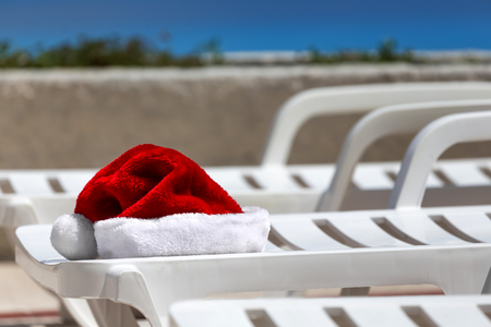 Santa Claus Hat on sunbed near swimming pool. Christmas vacation conceptの写真素材