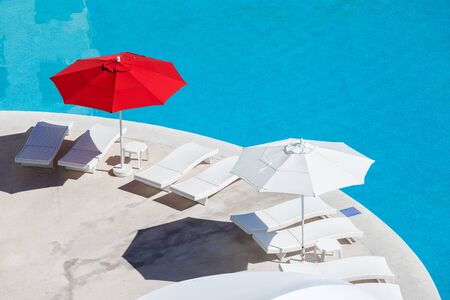 Sun umbrellas and beds near swimming pool at poolside. Vacation conceptの写真素材