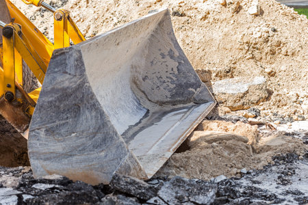 Road repair construction. Bulldozer bucket and broken asphalt, closeup