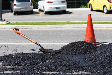 Shovel for road construction works in a heap of new asphalt at streetの写真素材