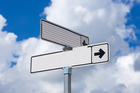 Blank white directional road signs over blue sky