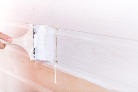 Woman painting wooden slot and key boards in white color with brushの写真素材