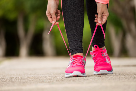Fitness woman tying running shoe laces, ready for jogging in summer park. Healthy lifestyle and sport conceptの写真素材