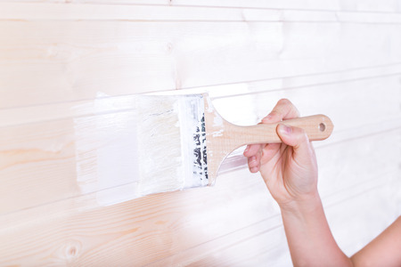 Woman painting wooden slot and key boards in white color with brushの写真素材