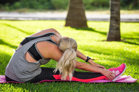 Fitness woman stretching her muscles before training, ready for jogging in summer park. Healthy...