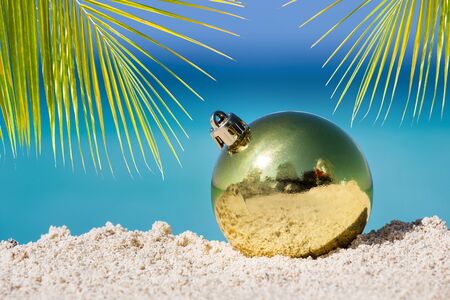 Yellow fir tree decoration ball on sandy beach, Tropical christmas and New Year celebrationの写真素材